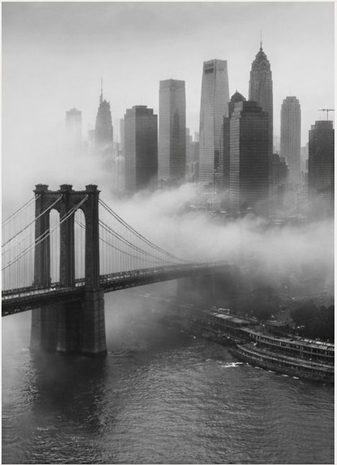 Suspension bridge leading into a skyline wrapped in fog